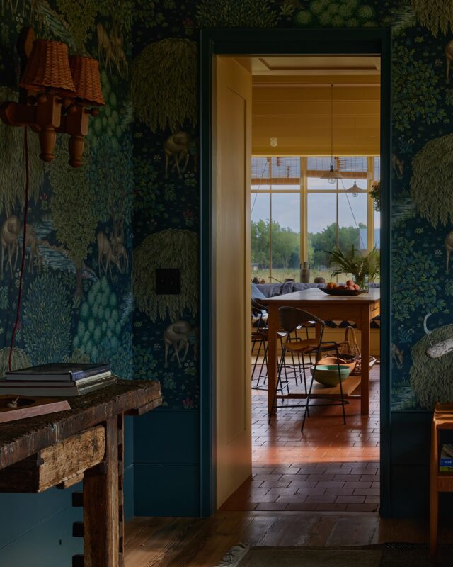 When approaching the family room, the wallpaper grabs your attention, though upon entering the room the view steals the show (as we feel it should). The house backs up to foothills of the Rocky Mountains, offering some of the most stunning sunsets you can imagine. Inside, we chose an enveloping pattern from the @williammorriscollection that felt deep and restful - a shady background for playing games or watching a movie.

Some of our favorite furnishings are in this room. Centered on the room sits an old carpenter’s workbench living a new life as a console, found at @howelondon. It was the first piece of significant furniture we sourced and set the tone for everything else. The large coffee table is a beloved piece from a childhood home, cradled within a custom sectional we designed, fabricated by our friends at @franciscan_interiors.

The room is grounded by an outdoor rug from @nanimarquina_official, which has already survived a blueberry smoothie incident (and probably other things we don’t know about). Behind it all hangs a quilted panel that we designed in collaboration with the marvelous Claudia of @mathildehome. It is a homey way for the family to reduce glare when needed, made reversible with metal grommets so it can be easily removed to enjoy the view without interruption. The red patches align on both faces so they appear to telegraph through the quilt.

Back outside, you can see that the volume of this room was popped out, which allowed us to get windows on three walls, break up the massing, and extend a lower roof to cover doors and patios. We clad the exterior with different siding to imply that it was an addition made down the line.

I’ll write another comment about the pool. @kloythanomsup likes to call me a “longcat” - I will not be contained!

The link to the feature is in our bio! 🏔️

Interior Architecture & Design: @landedinteriors #landedinteriors
Project Team: @heathermenegat, @rebeccamullerdesigns, Tiffany Kim, Luna Sibai, Laura Marx, Hanna Dooley
Architecture & Construction: @coburnpartners 
Landscape: @treeoflifelandscaping 
Photography: @yoshihiromakino 
Styling: @rainakattelson 
Publication: @archdigest